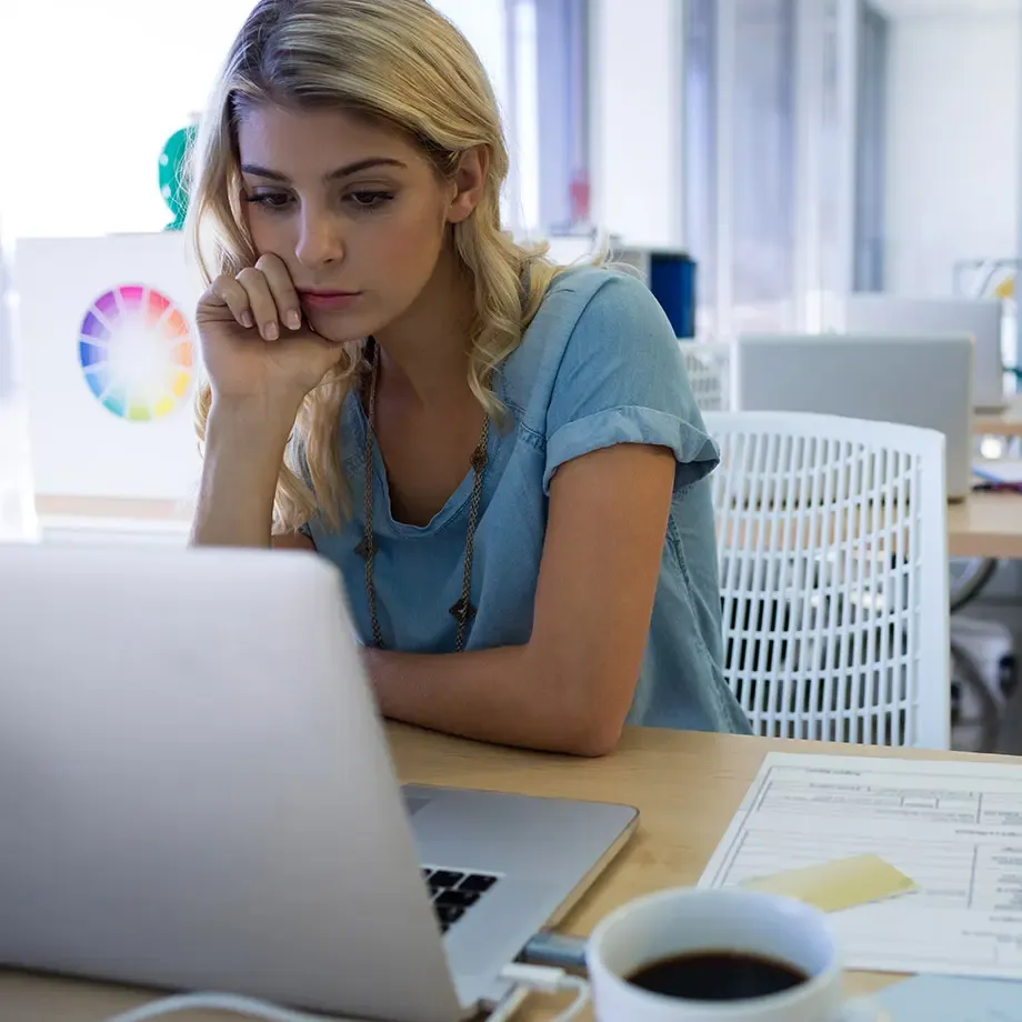 A woman feeling overwhelmed while working at her laptop